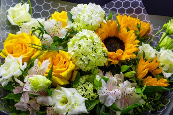 bright bouquet with yellow sunflowers and rose, pink eustoma and green viburnum floral background