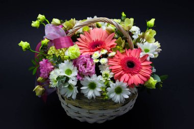 hasır sepette koyu bir arka plan çiçekler üzerinde beyaz bir sepet içinde parlak çiçek düzenleme