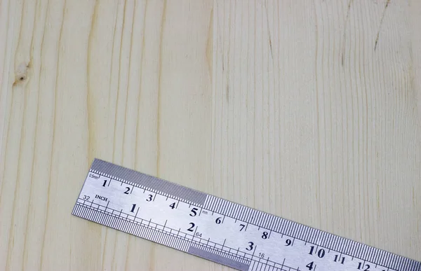 metal carpentry ruler on a light wooden background