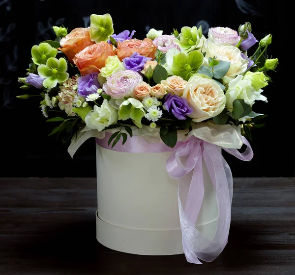 Belo arranjo de flores em uma caixa de chapéu em um fundo preto floral fundo — Fotografia de Stock
