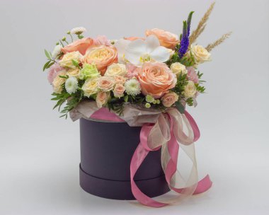 Beyaz bir arka planda bir şapka kutusunda farklı çiçekler karışık buket