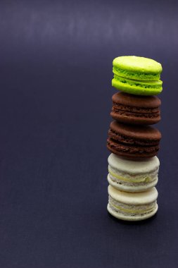 Koyu bir arka plan üzerinde renkli macaroons veya makarna kek. Bir Fransız tatlı incelik