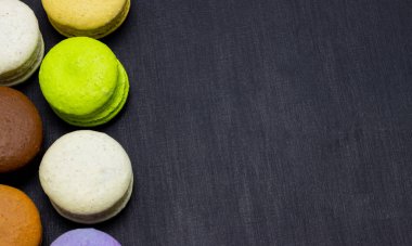 Koyu bir arka plan üzerinde renkli macaroons veya makarna kek. Bir Fransız tatlı incelik