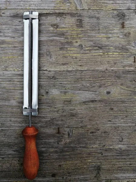 new clean file for sharpening the chain of an electric saw on a gray wooden surface close-up