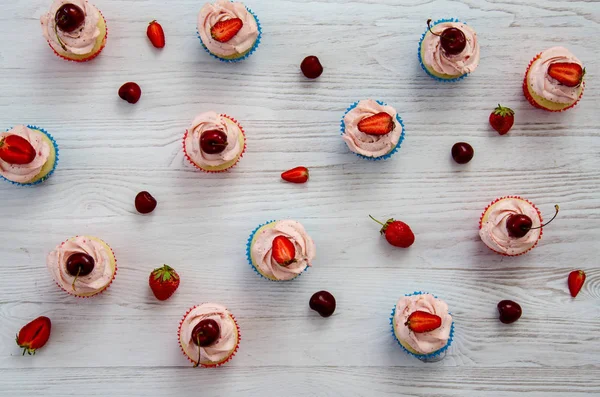 Viele Cupcakes mit weißer Sahne und Erdbeeren auf einem Holztisch — Stockfoto