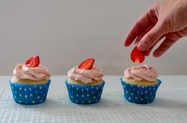 Mulheres mão decoração muffins com morangos brancos — Fotografia de Stock