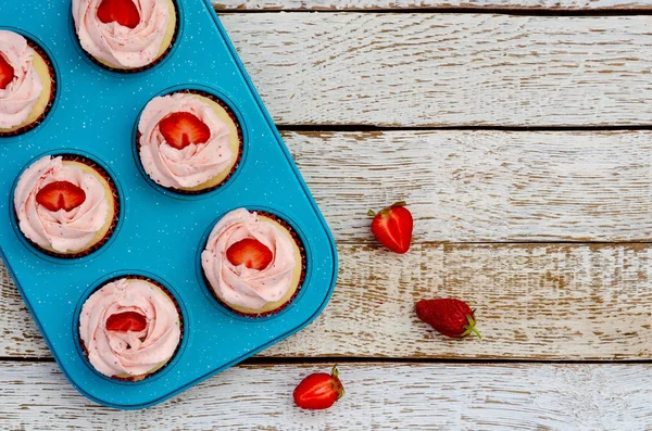 Cupcakes decorados en una mesa de madera blanca con fresas — Foto de Stock