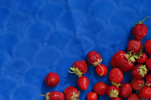 Ansicht von süßen und ganzen Erdbeeren auf blauem Tuch — Stockfoto