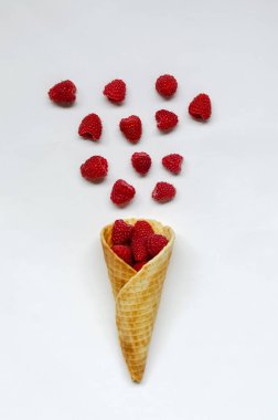 beyaz bir arka planda ahududu dolu dondurma koni.