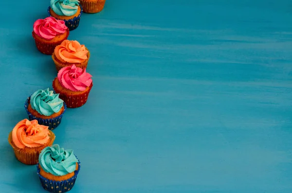 Die bunten hausgemachten Cupcakes auf blauem Hintergrund — Stockfoto