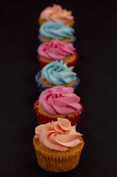 Os cupcakes caseiros coloridos em um fundo preto — Fotografia de Stock