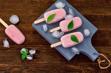 Ahşap arka planda taze ev yapımı çilek dondurması. Organik ve Vegan Popsicles