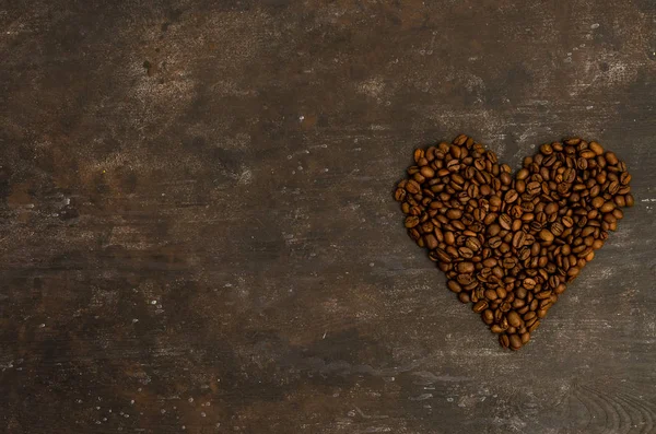 Кофе в бобах на темном фоне. Кофейные зерна в форме сердца. Текстура абстрактного фона. Фон питания кофейных зерен — стоковое фото