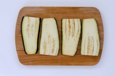 Patlıcan beyaz bir arka plan üzerinde ahşap kesme tahtası üzerinde dilimler halinde kesilmiş