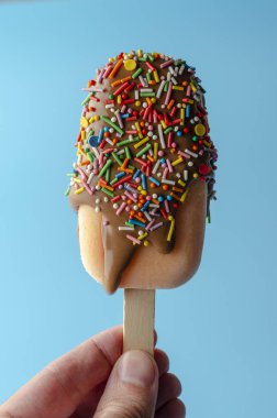 pastel açık mavi arka plan üzerinde dondurma çikolata sır tutan adam el.