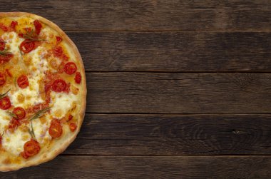 Ahşap arka planda İtalyan pizzası. Kiraz domates, parmesan peyniri ve biberiye.