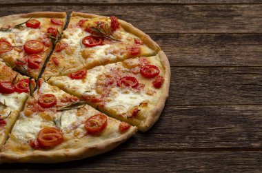 ahşap arka planda İtalyan pizza kesme. Kiraz domates, parmesan peyniri ve biberiye.