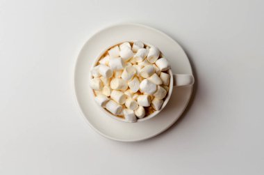 Bir tabak beyaz arka plan üzerinde beyaz bir fincan mini marshmallow ve tarçın ile Kahve