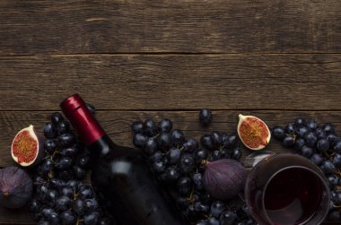 Şişede kırmızı şarap, peynir, üzüm, tahta da incir, arka plan