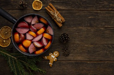 rustik ahşap masa üstü görünümünde baharat ve portakal dilimleri ile noel mulled şarap veya gluhwein stewpan. Kış tatilinde geleneksel içki.