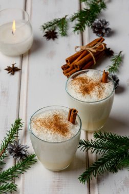 beyaz ahşap masa üzerinde noel dekorasyonu ile iki bardak eggnog kokteyl