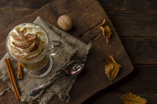 Tök latte tejszínhabbal, egy üvegedénybe egy rusztikus háttér — Stock Fotó