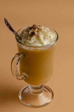 renkli bir arka plan üzerinde cam bir kavanozda krem şanti ile kabak latte