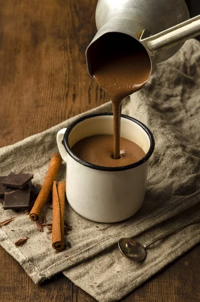 Bebida caliente de chocolate vertiendo en la taza en la mesa de madera —  Fotos de Stock