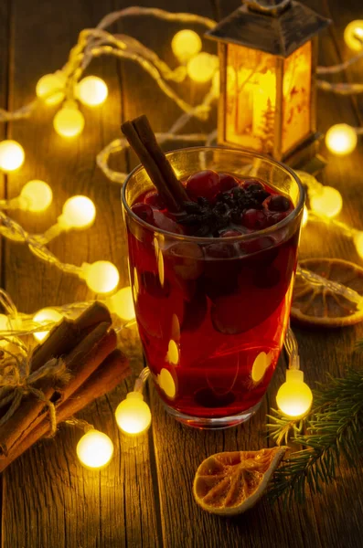 Sinaasappel- en veenbessenpunch met sinaasappelschijfjes en specerijen met kerstverlichting — Stockfoto