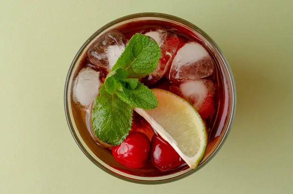 Cocktail rouge rafraîchissant à l'eau pétillante et glace garnie de citron vert et de cerise — Photo