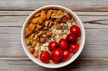 Bir kase yulaf ezmesi, taze böğürtlen ve sağlıklı kahvaltı için beyaz tahta üzerinde fındık.