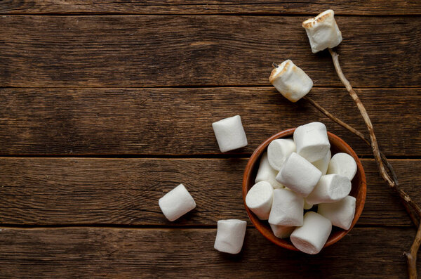 Marshmallow on the stick on wooden background