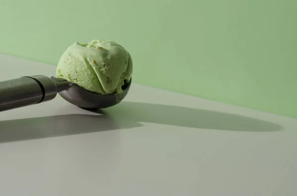 冰激凌勺，开心果冰激淋在淡绿色的背景上。时尚食品概念 — 图库照片