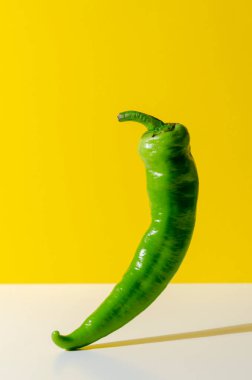 Sarı arka planda düşen yeşil biber ya da kırmızı biber.