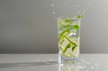 Limonlu mojito kokteyli ve uzun bardakta nane şekeri. Gri arka planda cam mojito..