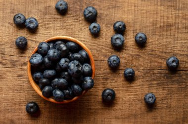 Ahşap arka planda bir kase yaban mersini.