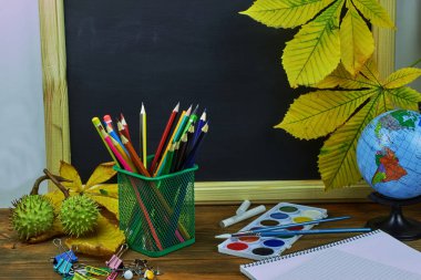 Okul konseptine geri dönelim. Sarı kestane yaprakları ile bir tahta arka plan üzerinde ahşap bir masa üzerinde Okul malzemeleri.