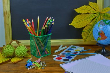 Okul konseptine geri dönelim. Sarı kestane yaprakları ile bir tahta arka plan üzerinde ahşap bir masa üzerinde Okul malzemeleri.