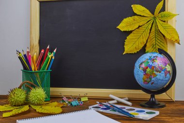 Okul konseptine geri dönelim. Sarı kestane yaprakları ile bir tahta arka plan üzerinde ahşap bir masa üzerinde Okul malzemeleri.