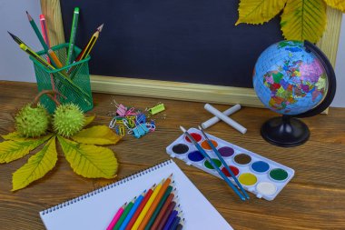 Okul konseptine geri dönelim. Sarı kestane yaprakları ile bir tahta arka plan üzerinde ahşap bir masa üzerinde Okul malzemeleri.