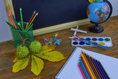 Okul konseptine geri dönelim. Sarı kestane yaprakları ile bir tahta arka plan üzerinde ahşap bir masa üzerinde Okul malzemeleri.
