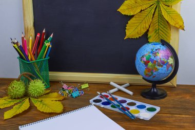 Okul konseptine geri dönelim. Sarı kestane yaprakları ile bir tahta arka plan üzerinde ahşap bir masa üzerinde Okul malzemeleri.