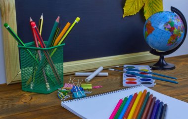 Okul konseptine geri dönelim. Sarı kestane yaprakları ile bir tahta arka plan üzerinde ahşap bir masa üzerinde Okul malzemeleri.