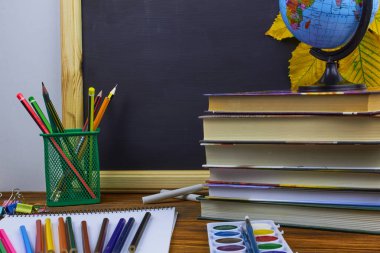 Okul konseptine geri dönelim. Okul malzemeleri ve kitaplar sarı kestane yaprakları ile bir tahta arka plan üzerinde ahşap bir masa üzerinde.