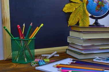 Okul konseptine geri dönelim. Okul malzemeleri ve kitaplar sarı kestane yaprakları ile bir tahta arka plan üzerinde ahşap bir masa üzerinde.