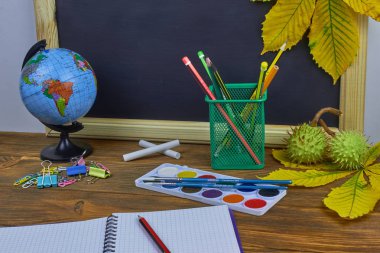 Okul konseptine geri dönelim. Sarı kestane yaprakları ile bir tahta arka plan üzerinde ahşap bir masa üzerinde Okul malzemeleri.