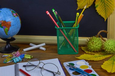 Okul konseptine geri dönelim. Sarı kestane yaprakları ile bir tahta arka plan üzerinde ahşap bir masa üzerinde Okul malzemeleri.