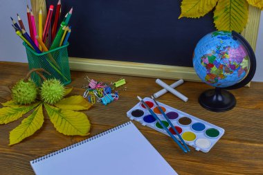 Okul konseptine geri dönelim. Sarı kestane yaprakları ile bir tahta arka plan üzerinde ahşap bir masa üzerinde Okul malzemeleri.