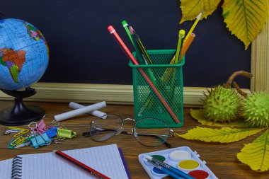 Okul konseptine geri dönelim. Sarı kestane yaprakları ile bir tahta arka plan üzerinde ahşap bir masa üzerinde Okul malzemeleri.