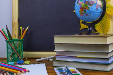 Okul konseptine geri dönelim. Okul malzemeleri ve kitaplar sarı kestane yaprakları ile bir tahta arka plan üzerinde ahşap bir masa üzerinde.